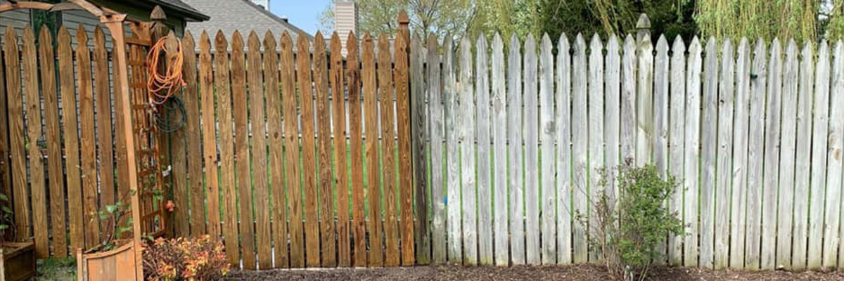 A wood fence with half restored and half aged